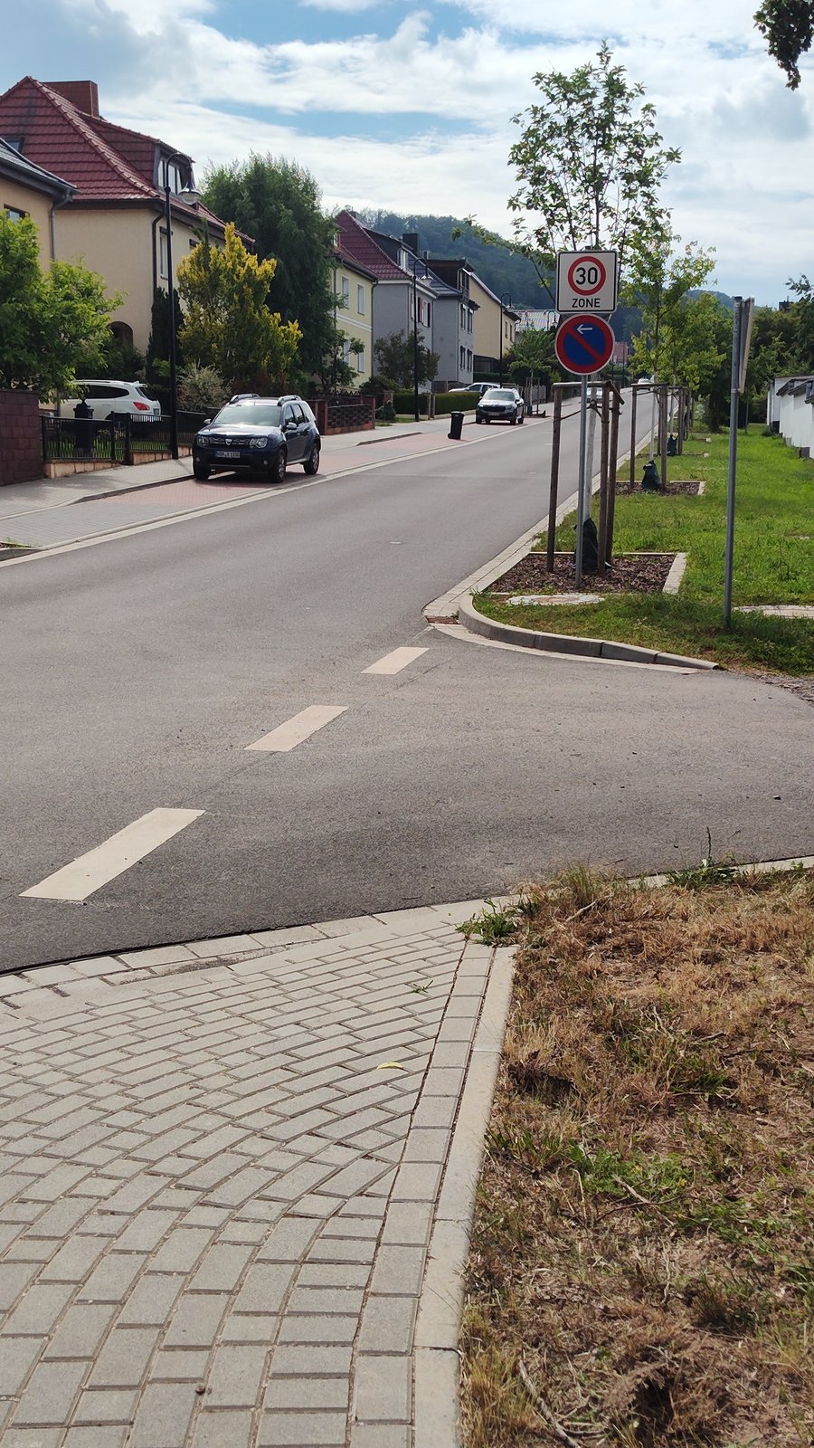 Blick in die erneuerte Johannes-Kleinspehn-Straße mit neuem Gehweg, Baumreihe und Nebenanlagen.
