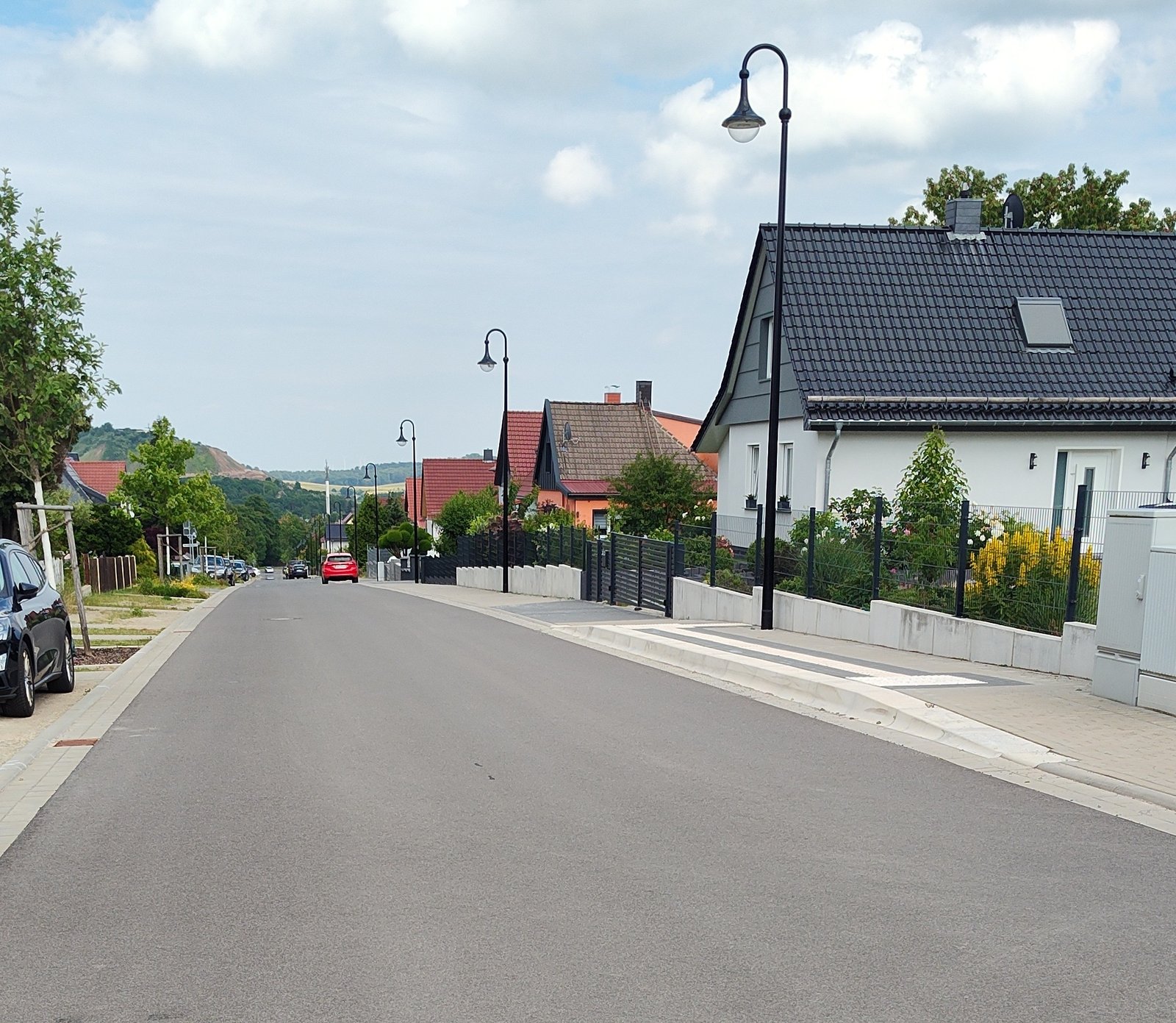 Johannes-Kleinspehn-Straße mit neuer Straßenbeleuchtung und barrierefreier ÖPNV-Haltestelle.